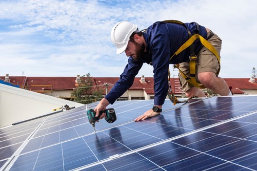 Image of a man installing solar panels. Learn about the direct and indirect benefits of solar panels.